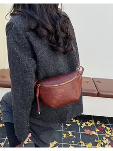Retro brown leather crescent saddle bag styled as a crossbody on a model in autumn scene