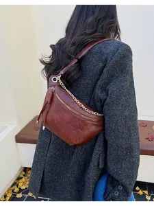 Close-up of retro brown leather crescent bag with chain strap and tassel details