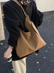 Brown vintage leather tote bag with white contrast stitching in an autumn outdoor setting