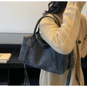 Detail of dark grey frosted leather Boston bag with round handles and adjustable side buckles