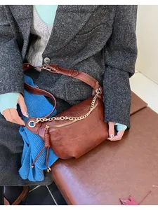 Detail of vintage brown crossbody bag featuring gold chain and textured leather material