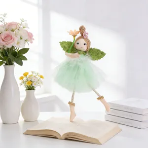 Detail of fairy ornament with green tulle skirt and white feathers in floral setting