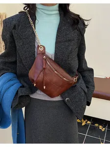 Detail of dark brown semi-moon crossbody bag with gold chain strap and tassel charm