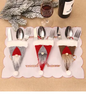 Trois porte-couverts de Noël gnome en gris, rouge et marron sur une table de fête
