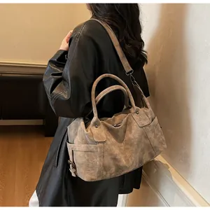 Detail of vintage matte leather travel tote showing handles and detachable shoulder strap