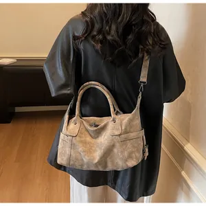 Detail view of large taupe travel tote showing textured leather and side pocket on shoulder