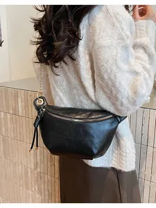 Detail of black faux leather half-moon bag with gold zipper and chain strap