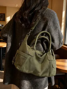 Olive green large capacity tote bag worn by a model in an elegant cafe setting