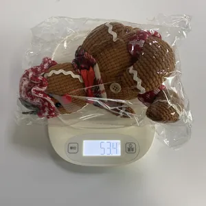 Gingerbread man plush ornament in clear polybag packaging shown on a digital scale