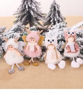 Group of plush Christmas angel dolls in white and pink tones on rustic linen background