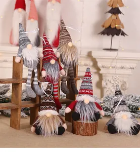 Close-up detail of knitted Christmas gnomes with long hats and faux fur beards on wood