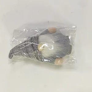 Detail of a handmade plush Christmas gnome with gray knit hat and white beard in packaging