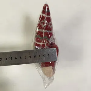 Detail showing red knitted Christmas doll thickness being measured with a metal ruler