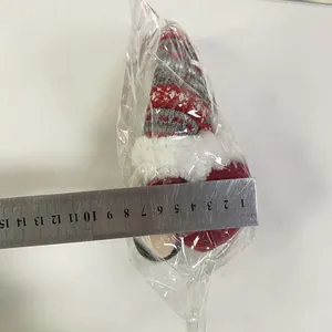 Detailed size measurement of a plush Christmas gnome in plastic packaging with a steel ruler