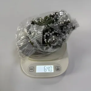 Detalle de un mini árbol de Navidad de 20cm con bayas blancas y base de rayas en báscula