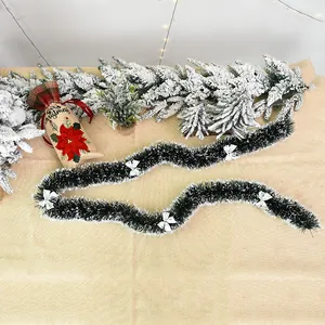 Dark green Christmas tinsel garland with white tips and silver bows for holiday party decor