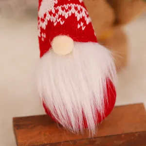 Knitted Christmas gnome ornament with red patterned hat and long white beard on wood