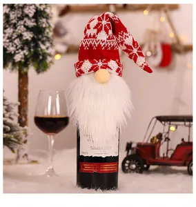 Festive red and white knitted gnome wine bottle cover with long beard on a dinner table