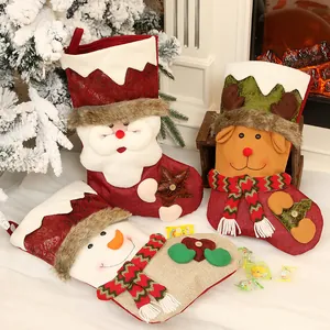 Trois chaussettes de Noël décoratives avec Père Noël, renne et bonhomme de neige près du feu