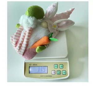 Gnomo pasquale di peluche con orecchie da coniglio e carota che pesa 119g sulla bilancia