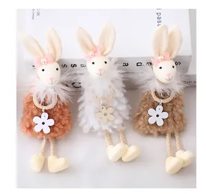 Dettaglio di tre coniglietti pasquali di peluche con sciarpe di piume e piedi a cuore