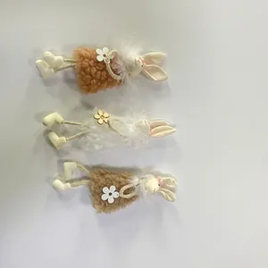 Tre coniglietti pasquali di peluche con collari di piume e gambe in corda intrecciata