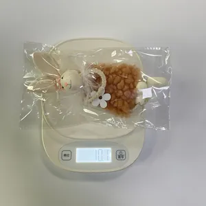 Dettaglio del ciondolo a forma di coniglio di peluche marrone pesato su una bilancia bianca