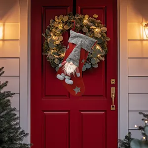 Red Christmas stocking with gnome applique hanging on a festive front door with warm lights