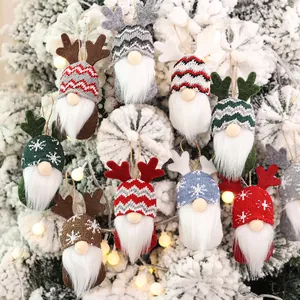 Charming knitted Christmas gnome ornaments with reindeer antlers on a snowy tree background