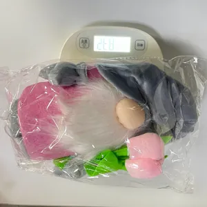 Detail shot of Mother's Day gnome plush with tulip on a scale showing 268g weight