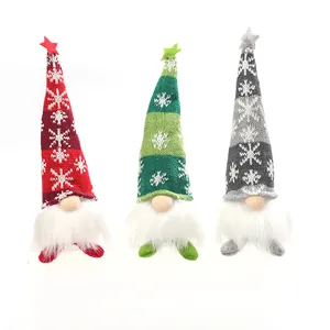 Tre gnomi di Natale luminosi con cappelli a maglia e stelle su basi espositive bianche