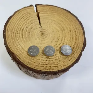 Detailed view of three AG10 button cell batteries displayed on a rustic wood slice background
