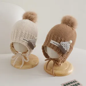 Detail of knit baby hats with pom-poms, ear flaps and warm lining for toddlers