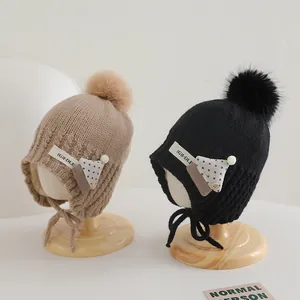 Winter knit baby hats with pom-poms and earflaps in khaki and black colors