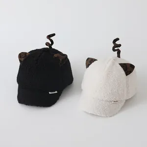 Detail of plush baby baseball caps in black and cream with cute leopard ears and texture