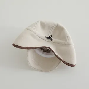 Dettaglio del cappello in pile beige con bordo marrone e coulisse di regolazione posteriore