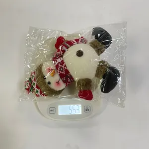Detail view of plush snowman ornament on electronic scale showing weight of 55.3 grams