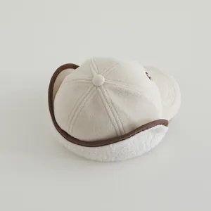 Dettaglio del cappello beige per bambini con morbida fodera in pile e bordo marrone
