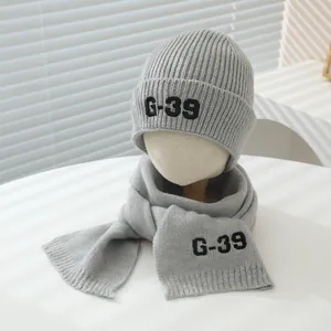 Detail view of grey knitted beanie and scarf set featuring G-39 letter embroidery