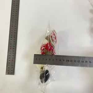 Close-up of a glowing Santa plush ornament with a ruler for size reference and scale