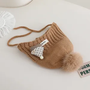 Detail view of knit winter baby hat featuring warm brown yarn and a soft pom-pom