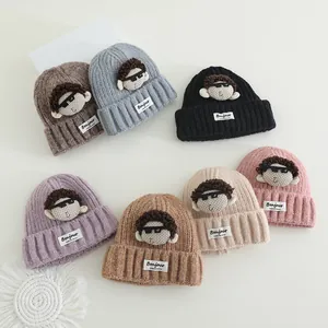 Dettaglio di berretti in maglia per bambini in sette colori con toppe a cartone animato