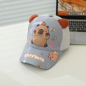 Detail of grey capybara kids baseball cap with 3D ears and cartoon print on desk