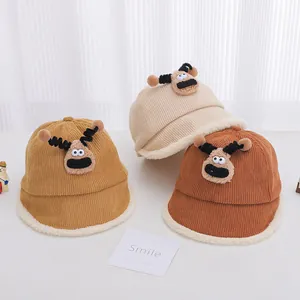 Close-up of children's corduroy bucket hats in yellow and beige with cartoon deer dolls