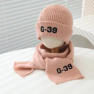 Detailed view of pink knitted beanie and scarf set with black G-39 letter embroidery