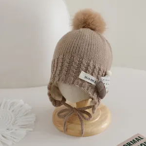 Close-up of knit texture and heart pendant on a beige winter hat for kids