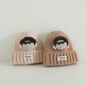 Dettaglio di cappelli in maglia beige e marrone chiaro con toppe di cartoni animati