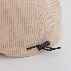 Close-up of adjustable drawstring and spring buckle on beige corduroy bucket hat