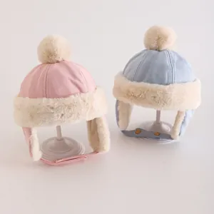 Details von rosa und blauen Kinder-Wintermützen mit Kunstfellfutter und weichen Bommeln