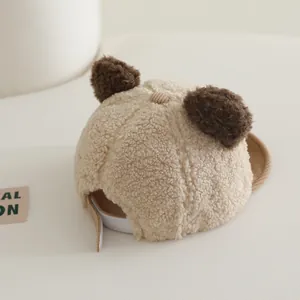 Detail of plush beige baby bear hat with brown corduroy brim and adjustable strap